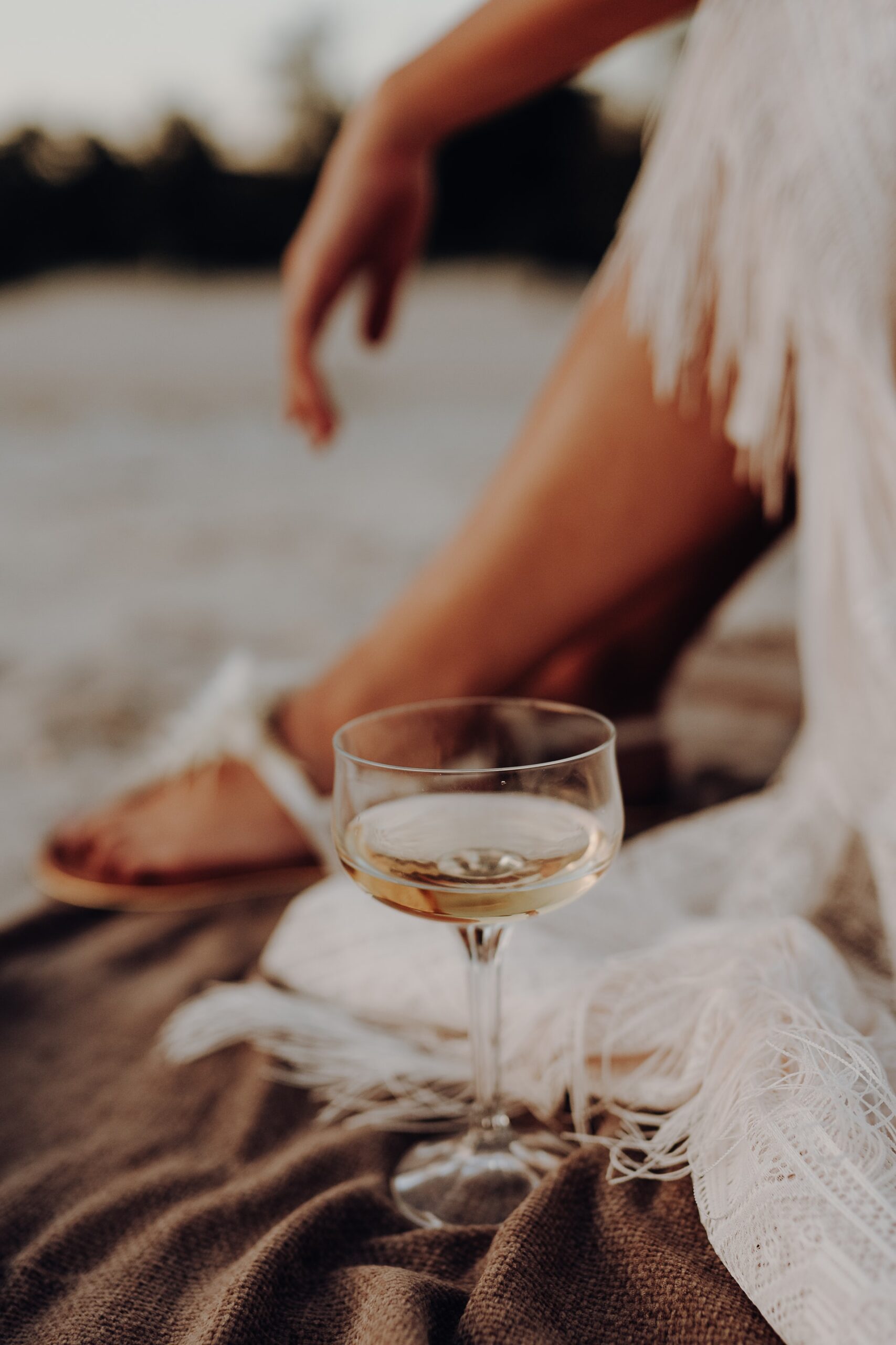 close up of woman sitting with a cocktail next to her foot