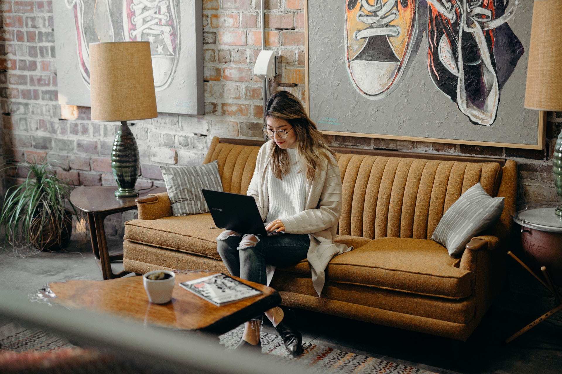 woman sitting on couch writing on laptop