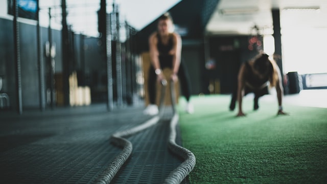 blurred image of a woman exercising using a battle rope