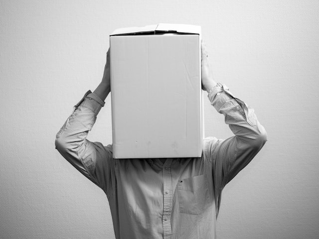 a black and white image of a person standing with a box on their head