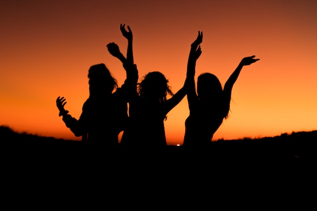 Silhouette of women standing in a group with hands in the air